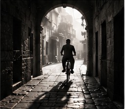 Cyclist passing through a historic street archway